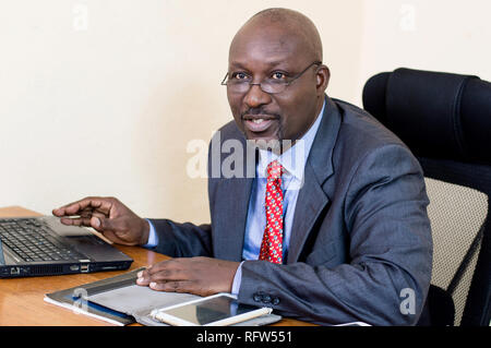 Smiling businessman working on his laptop in the office and looking at the camera. Stock Photo