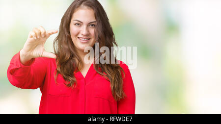 Beautiful plus size young business woman over isolated background smiling and confident gesturing with hand doing size sign with fingers while looking Stock Photo