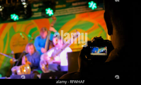 Unrecognizable professional videographer silhouette recording video of live music folk concert with digital mirrorless camera at night. Photography, e Stock Photo