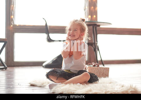 happy little girl sitting on the carpet in the living room.