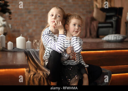 two little sisters talk sitting in a cozy living room . Stock Photo