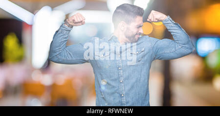 Young handsome man over isolated background showing arms muscles smiling proud. Fitness concept. Stock Photo