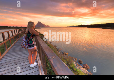 A girl looks at sunrise from a walkway, Porto Taverna, Loiri Porto San Paolo, Olbia Tempio province, Sardinia, Italy, Mediterranean, Europe Stock Photo
