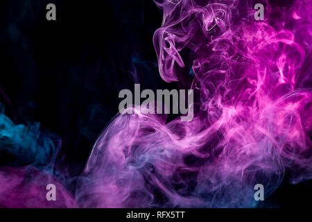 Dense multicolored smoke of   pink and blue colors on a black isolated background. Background of smoke vape Stock Photo