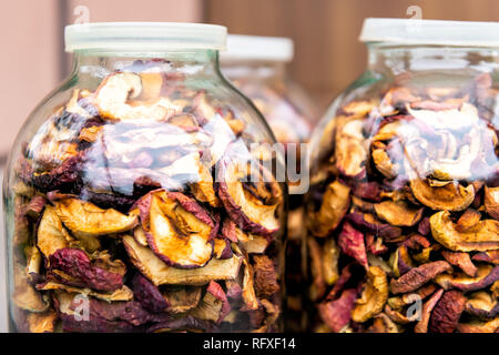 Dehydrated pink purple colorful dry homemade pieces apple fruit slices stored in many glass jars macro closeup Stock Photo