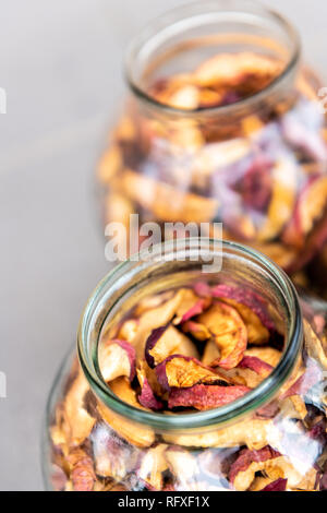 Dehydrated pink purple colorful dry homemade pieces apple fruit slices stored in many glass jars top macro closeup Stock Photo