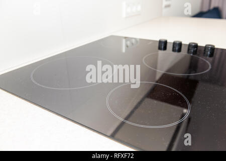 Macro closeup of modern luxury electric cook stove top stovetop cooktop with glass reflection and circles background in empty home Stock Photo