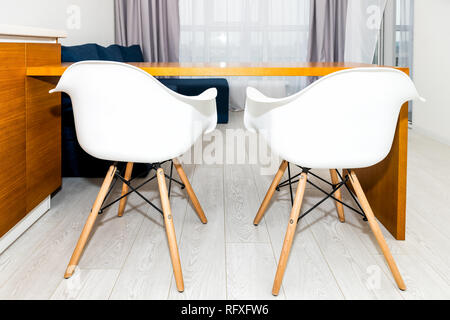 Modern wooden brown orange kitchen features cabinets in small apartment studio with two bar stools interior design and nobody in minimalist home Stock Photo