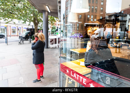 London, UK - September 12, 2018: Neighborhood of Pimlico Victoria with woman standing on sidewalk by Pret A Manger modern cafe restaurant window refle Stock Photo