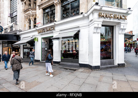 London, UK - September 12, 2018: Sidewalk street shopping at Leicester Square stores during day in city with Shake Shack restaurant