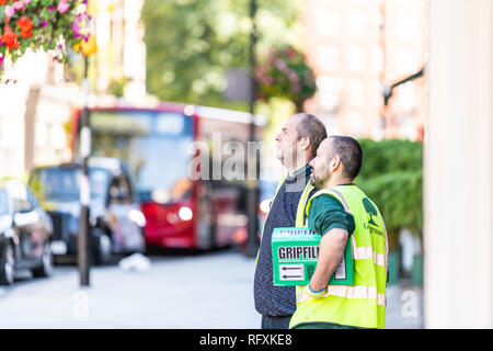 London, UK - September 13, 2018: Street in Belgravia area with two men construction workers standing looking up with defocused background Stock Photo