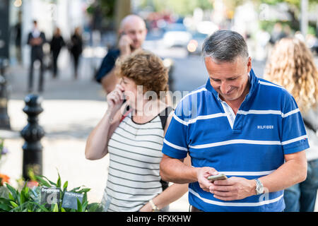 London, UK - September 13, 2018: Chelsea shopping area with people walking on street pavement pedestrians and happy older couple standing smiling Stock Photo