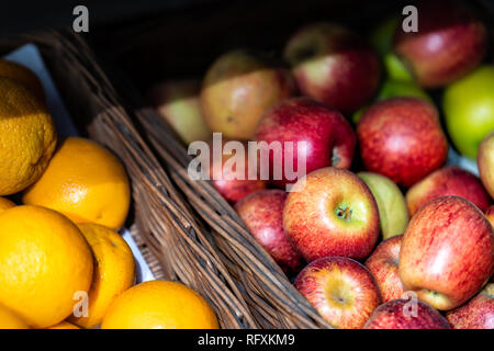 Closeup of many red apples and oranges in baskets at farmer's market shop store showing detail and texture assortment Stock Photo