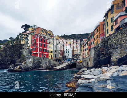 Riomaggiore is the first stop on many Cinque Terre visits. Peeling buildings line up down a steep ravine to a tiny harbour. Stock Photo