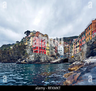 Riomaggiore is the first stop on many Cinque Terre visits. Peeling buildings line up down a steep ravine to a tiny harbour. Stock Photo