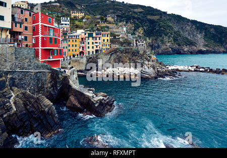 Riomaggiore is the first stop on many Cinque Terre visits. Peeling buildings line up down a steep ravine to a tiny harbour. Stock Photo