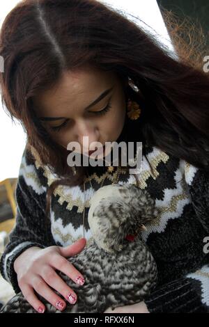 Long haired girl on a farm kisses a fluffy chicken Stock Photo