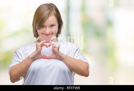 Young adult woman with down syndrome over isolated background smiling in love showing heart symbol and shape with hands. Romantic concept. Stock Photo