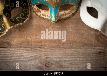 Three venetian carnival masks for mardi gras parade on wooden table Stock Photo