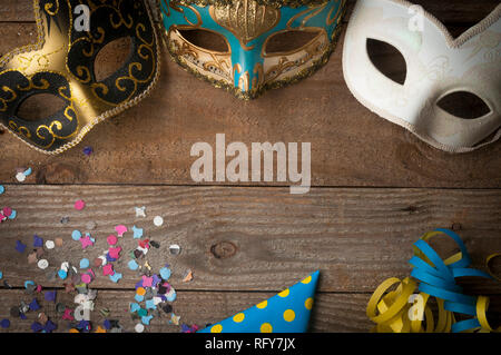 Mardi gras masks on wooden table with streamers and confetti Stock Photo