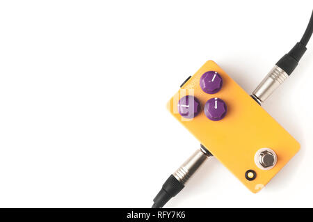 Orange guitar pedal with purple knobs and plugged jacks on white background Stock Photo