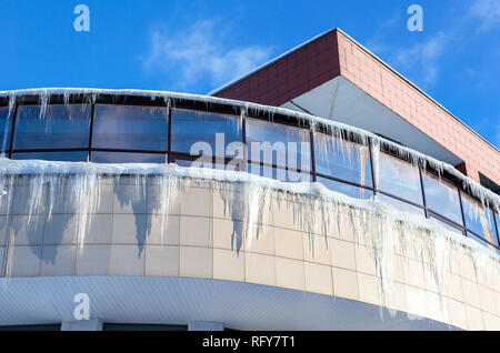 Transparent icicles on the roof of the house in sunny winter day Stock Photo