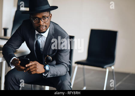 handsome serious man in stylish outfit resting in the chair in the office Stock Photo