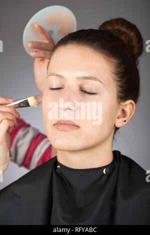 Make-up artist applying powder on model's face Stock Photo