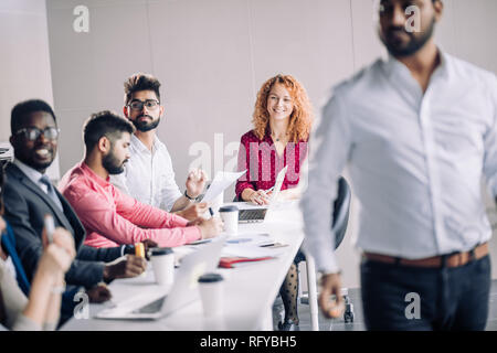 Mixed race people listening to presentation sitting in row at boardroom table Stock Photo