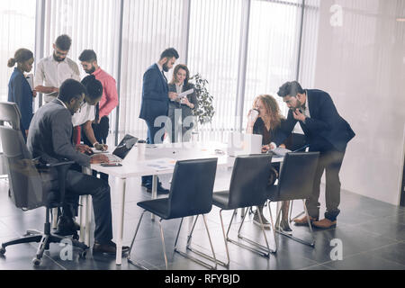 Diverse smiling businesspeople having conversation standing together at meeting. Stock Photo