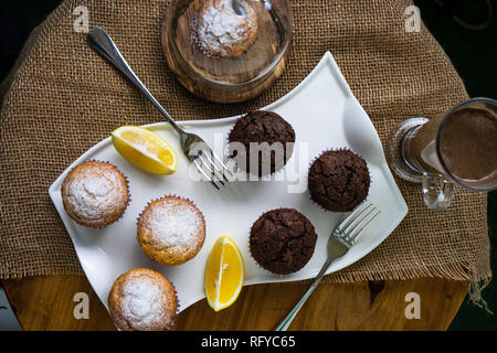 Tasty lemon and chocolate cupcakes in rustic interior Stock Photo