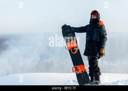 handsome cool man with snowboard on mountain top. Stock Photo