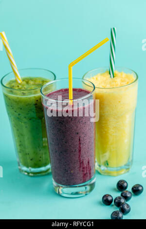 Three various milkshakes in glasses on the isolated blue background. Stock Photo
