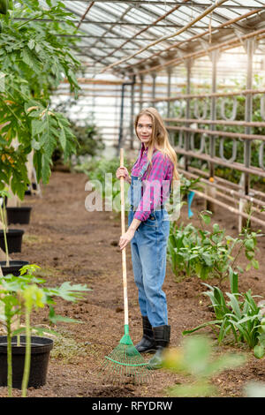 awesome pretty woman is looking at the camera while working in the greenhouse Stock Photo