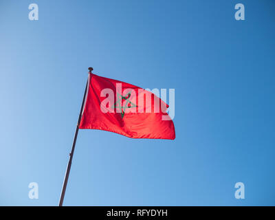 Morrocan flag on flag pole against blue sky, no clouds, copyspace Stock Photo