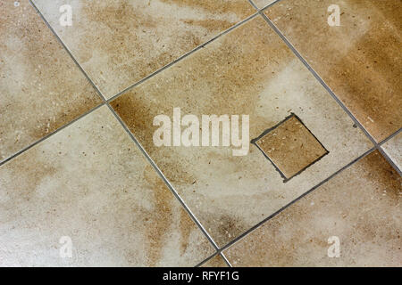Abstract background, seamless pattern of light beige old ceramic tiled floor or wall with hole and repaired patch indoors. Stock Photo