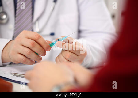 Physician injector arms in sterile uniform holding syringe Stock Photo