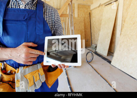 Construction worker pointing at digital tablet at construction site Stock Photo