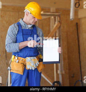 Worker pointing at a clipboard with blank paper, contract concept Stock Photo