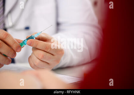 Physician injector arms in sterile uniform holding syringe Stock Photo