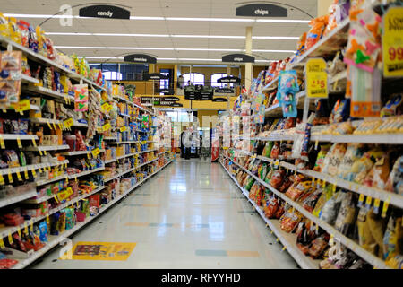 Grocery store aisle with shopper and shopping cart. Stock Photo