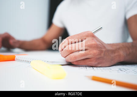 Close-up of hands architect uses laptop and building blueprint on working table in office space. Young engineer working on building plan Stock Photo