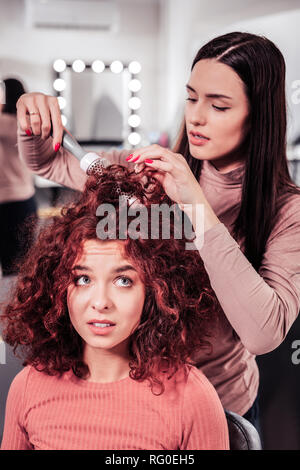 Nice serious woman doing professional hair styling Stock Photo