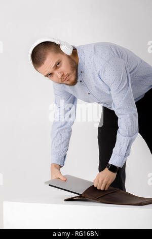 businessman in headphones puts laptop in cover Stock Photo