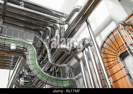 Steel pipelines and cables in factory interior as chemical industry background concept Stock Photo