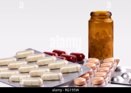 Close-up view of colorful pills and capsules of brown medicine bottles on blurred white background with space for text Stock Photo