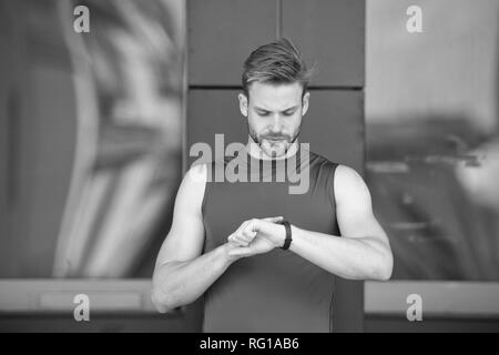 Set up route. Man athlete busy face check fitness tracker urban background. Athlete with bristle looks at fitness tracker or pedometer. Sportsman training with pedometer gadget. Sport gadget concept. Stock Photo