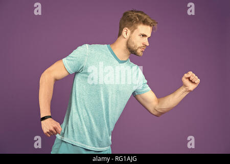 Man in tshirt and shorts on violet background. Runner in blue casual clothes on purple background. Sportsman in active wear for running. Sport fashion style and trend. Fitness and gym activity. Stock Photo