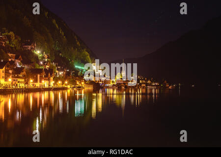 Hallstatt at night with reflections of the buildings in the lake and ...