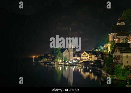 Hallstatt at night with reflections of the buildings in the lake and ...